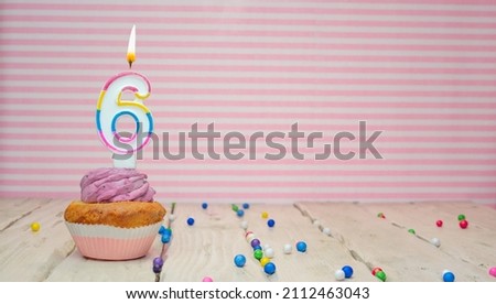 Muffin with cream and number 6 for birthday on a pink background, copy space, holiday background. Happy birthday greetings for a six year old child.