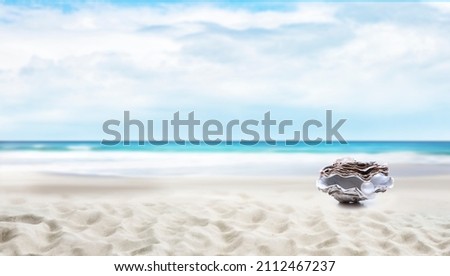 Oyster with pearl on beach with sea in background