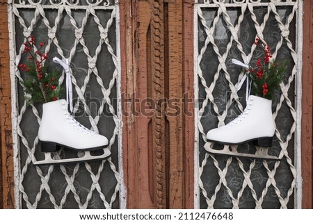 Pair of ice skates with Christmas decor hanging on old wooden door