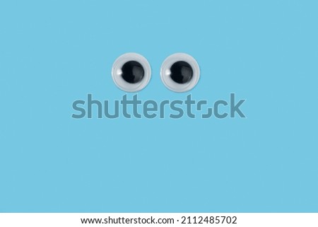 Googly eyes on a light blue background with copy space
