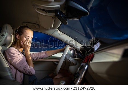 Young female driver at the wheel of her car, super tired, falling asleep while driving in a potentially dangerous situation - Road safety concept Royalty-Free Stock Photo #2112492920