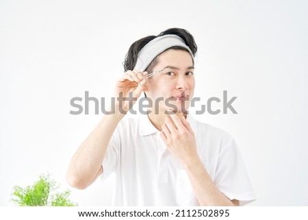 Asian man cutting eyebrows in white background