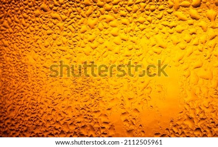 macro beer drink,Water drops background,Close up drops of a Ice Cold Pint of Beer- condensation. The background is clear with the emphasis on water drops on yellow-golden background.