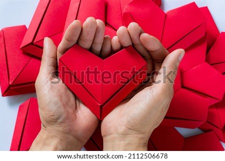 paper heart,Hands Holding Folded Origami Heart White Background,Little boy's hand holding red heart paper on blue background