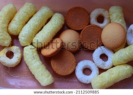 Children's snack. Toddler nibbles. Rice and corn extruded foods. Travel food. Gluten-free diet. Nutrition for children. Royalty-Free Stock Photo #2112509885