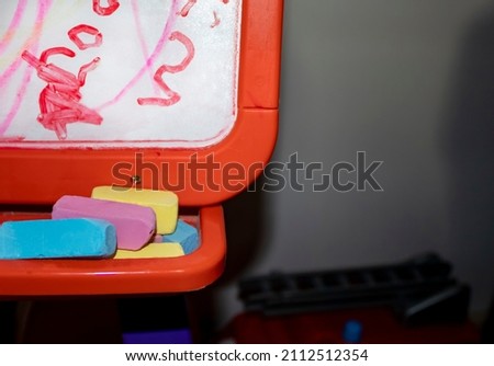 Colored Chalks Chalkboard. Chalk on the board. Red-pink Plastic Magnetic Drawing Board on a Light Background. The concept of children's educational toys.