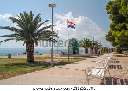 Monument to the Fallen in the War for the Fatherland and palm tree on the beach by the sea, Omis, Croatia Royalty-Free Stock Photo #2112523703