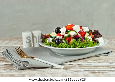Greek salad on a white background. Salad in a plate on an old wooden table.