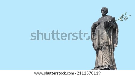 Banner with old statute of poet, writer with book, Bible and laurel branch at Cathedral of Holy Trinity, historical center of Dresden, Germany, at blue sky solid background with copy space