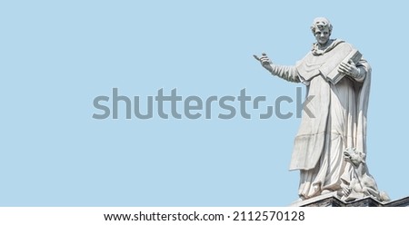 Banner with old statute of poet or writer with book, Bible and dragon at Cathedral of Holy Trinity, historical center of Dresden, Germany, at blue sky solid background with copy space