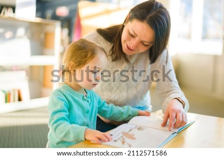 A Mother and child looking picture books together at the library