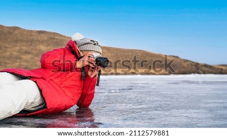 Tourist photographer with a camera on the ice of Lake Baikal.