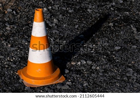 Orange construction cone on a gravel floor