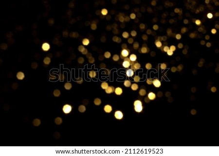 Golden blurred bokeh lights on black background. Glitter sparkle stars for celebrate. Overlay for your design Royalty-Free Stock Photo #2112619523