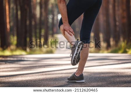 Woman feeling pain of her leg during jogging. Calf muscle cramp. Underestimating the warm-up exercise before running Royalty-Free Stock Photo #2112620465