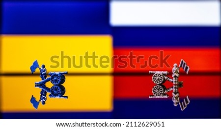Conceptual image of war between Russia and Ukraine using toy soldiers and national flags on a reflective background Royalty-Free Stock Photo #2112629051