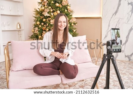 Young woman doing self portrait indoors. Home vacation portrait. Blogger selfie. Alone in interior. Happy emotion. Smiling female person. Lifestyle Christmas action. Posing christmas