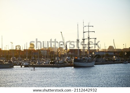 Yachts and motor boats in La Marina de Valencia. Luxury yacht and fishing motorboat in yacht club on sunset. Skiff and Sailboat in port. Yachting and sailing sport. Quai at ​Dock at Mediterranean Sea.
