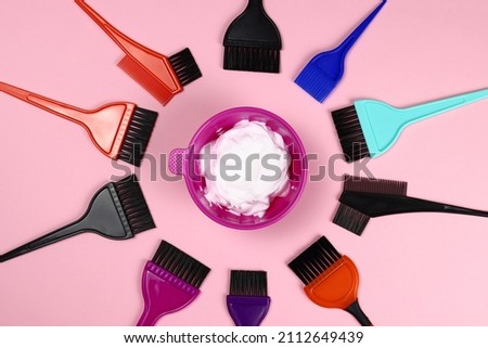 Hair coloring tools - plastic bowl with hair dye and brushes on pink background Royalty-Free Stock Photo #2112649439