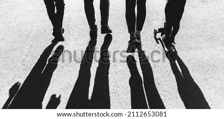 Silhouettes of young people in the backlight. Young family dad, mom and two children walk along the path in the park in the rays of the setting sun Royalty-Free Stock Photo #2112653081