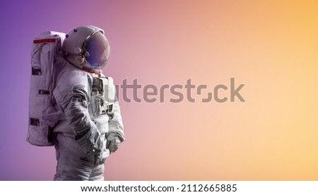Astronaut stay on isolated background with gradient. Spaceman in space suit. Creative sci-fi space wallpaper. Elements of this image furnished by NASA Royalty-Free Stock Photo #2112665885
