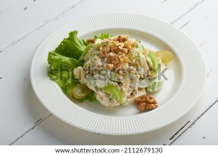 classic american waldorf salad made of apples celery walnuts grapes mayonnaise whipped cream white plate white background
