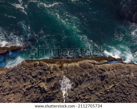 View from above. Sea foamy waves break on a rocky shore. Clear clear turquoise water. Ecology, environmental protection, geology, biology. Advertising of tourist destinations.