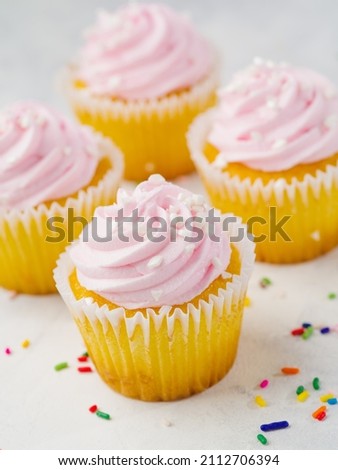 macro photography. Cupcakes with protein berry pink cream, multi-colored confetti are scattered on a white background. Romantic date, birthday, anniversary, family holiday.