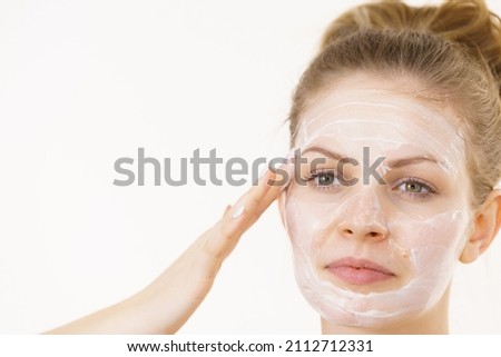 Young woman applying facial cream cosmetic, mask moisturizing to her face. Perfect skin. Beauty, wellness and skincare.