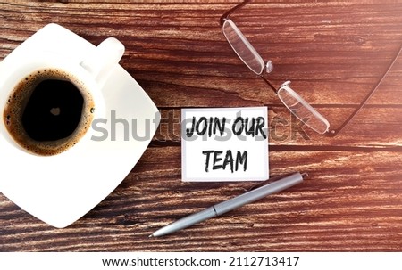 JOIN OUR TEAM text on the sticky with coffee,pen and glasses on wooden background