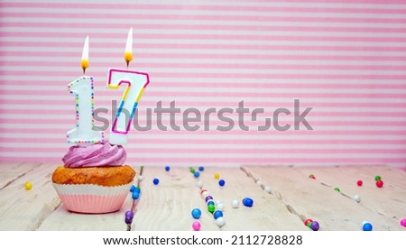 Muffin with cream and number 17 for a birthday on a pink background, copy space, holiday background. Happy birthday greetings for seventeen years old Royalty-Free Stock Photo #2112728828