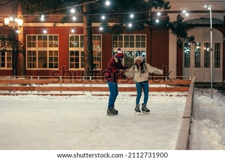 Young multiracial couple laughing and being silly on the ice of a outdoors rink