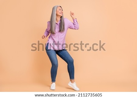 Full size photo of sweet white hairdo elder lady dance wear violet shirt jeans footwear isolated on beige background