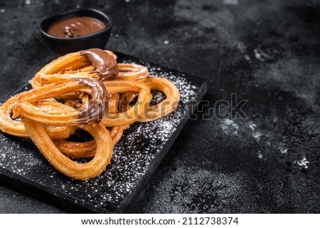 Traditional mexican dessert churros with chocolate sause. Black background. Top view. Copy space