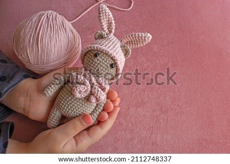 Handmade knitted toy. Amigurumi rabbit toy. Crochet stuffed animals.pink background.