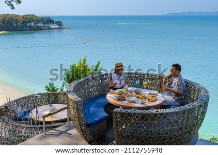 couple having lunch at a restaurant looking out over the ocean of Pattaya Thailand, man and woman having dinner in a restaurant by the ocean in Pattaya.  Royalty-Free Stock Photo #2112755948