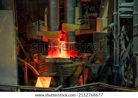 Electric arc steelmaking furnace, thick powerful red-hot graphite electrodes Royalty-Free Stock Photo #2112768677
