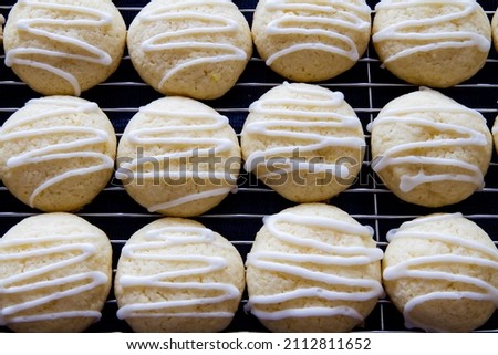 Rows of fresh homemade lemon sugar cookies with drizzled icing; Pretty white cookies with zig zag icing pattern