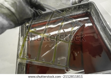 The process of manual washing of polymer printing plates in a special solution dissolving the paint. Work in a printing house. Selective focus