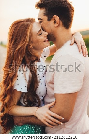 Beautiful young caucasian couple embracing and smiling while standing outdoors. Beautiful summer landscape. Summer vacation. Royalty-Free Stock Photo #2112812210