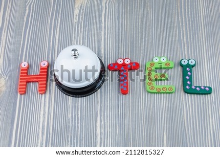The word hotel from colored letters on a wooden table. Desk bell for reception.