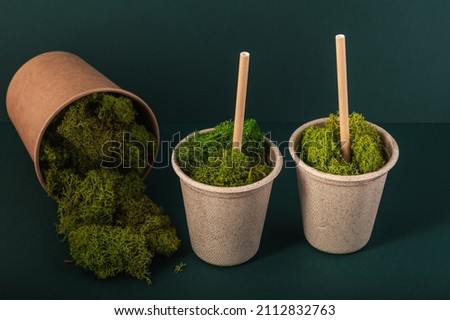 Recycled paper cups on a green background, green moss. Zero waste concept.