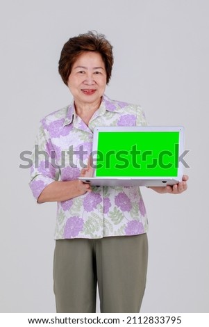 Senior Asian woman happy to demonstrate banner display of recommended laptop to show advertising message for sale promotion offer and info presentation in public business education class for adult.