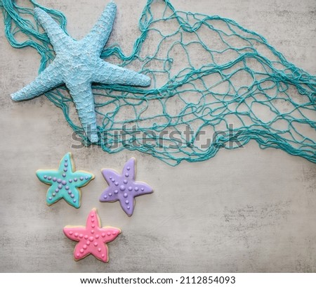 Star fish sugar cookies with royal icing on a sea theme surface with fishing net.