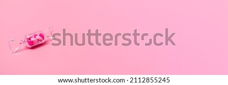 Transparent box in the shape of a candy with sweet heart lollipops on a pink background with copy space. Banner