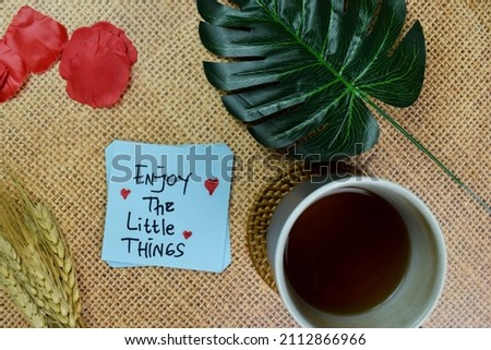 Enjoy The Little Things write on sticky notes isolated on Wooden Table.