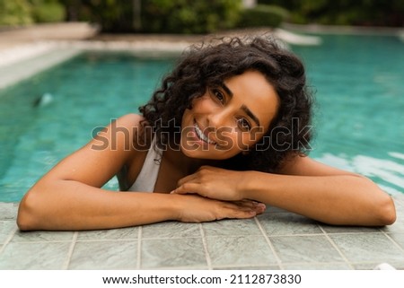 Summer portrait of beautiful  woman with perfect tann skin chilling in pool while tropical vacation.