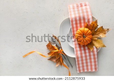 Composition with table setting, pumpkin and autumn leaves on white background