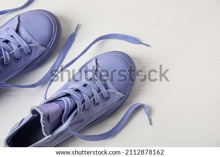 Pair of stylish shoes with untied laces on light wooden background, closeup
