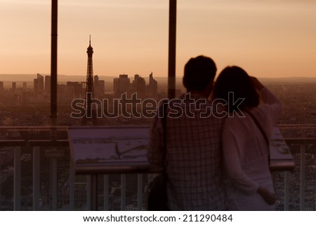 Couple in love at Paris admire Eiffel Tower at sunset
